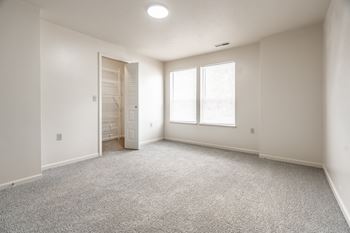 A room with a carpeted floor and a door leading to another room.